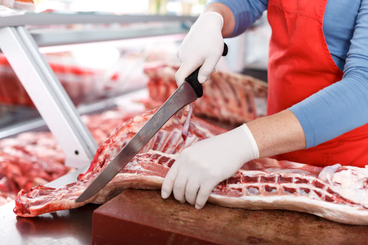 Açougueiro cortando carne no balcão do açougue